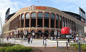 The exterior of a baseball stadium, which has a round brown entrance area with a white and orange "citiFIELD" on top.