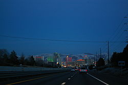 Dusk view of a freeway descending into a neon lit cityscape