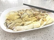 Handmade rice noodle rolls in a plate with a pair of black chopsticks