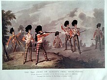 Seven soldiers in action, in red tartan trews, with red coats and black feather bonnets, and one with a tartan shoulder plaid; most have rifles
