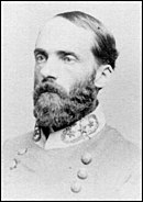 Black and white photo of a bearded man with a receding hairline. He wears a gray military uniform with three stars on the collar.