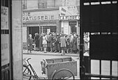 People queuing in the street outside a bakery