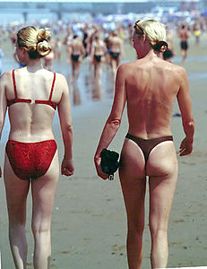 Some female clothing, such as the bikini or panties, show part of the female buttocks (woman on left). Thongs, in particular, leave almost all of the buttocks exposed (woman on right). Photo is of a beach in Holland, 1999.