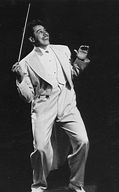 Calloway, dressed in white tie and tails, holding an elongated conductor's baton