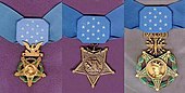 Three medals, side by side, consisting of an inverted 5-pointed star hanging from a light blue ribbon with 13 white stars in the center. Left medal has a laurel wreath around the star and an eagle emblem above the star; central medal has an anchor emblem attaching the medal to the ribbon; rightmost medal has a laurel wreath around the star and an emblem with wings, lightning bolts and the word "VALOR" connecting the medal to the ribbon.