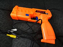 Chunky, bright orange light gun with black RCA cables attached
