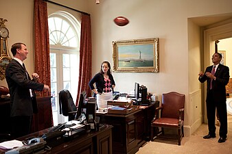 President Barack Obama tosses a football with Trip Director Marvin Nicholson in the outer Oval Office on June 26, 2009. Personal Secretary Katie Johnson watches from her desk.