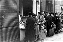 Street scene of people queueing outside a shop