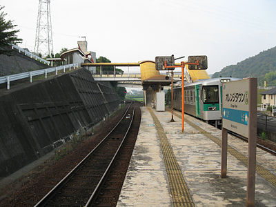 A view of the station platform. The station building can be seen to the left. The footbridge extends to the right, permitting access to the station from the other side of the tracks.