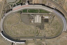 An aerial view of an oval-shaped motor-racing circuit.