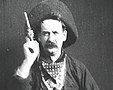 An outlaw raising his gun toward the camera