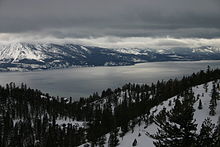 Photo of a large lake surrounded by mountains under heavy cloud cover