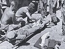 A Hospital Corpsman prepares a wounded Marine for evacuation from a forward aid station in the Yanggu area.