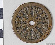 A charm coin with a centre hole encircled by eight Chinese characters, with an outer circle of sixteen Chinese characters
