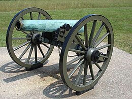Photo shows a Civil War era cannon. Its bronze barrel has a pale green patina from weathering.