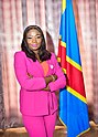 Portrait of Christelle Vuanga standing next to a flag of the DRC