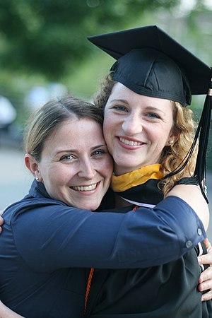 Two people hugging; one with a graduation cap