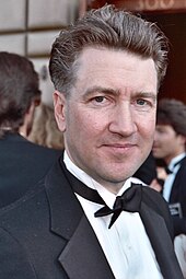 A man in a tuxedo smiles at the camera.