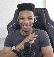 Desmond Amofah pictured in May 2019 sitting in a gaming chair, looking and smiling at the camera