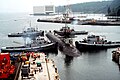 Naval Submarine Base Bangor with tug Mishawaka (rear left) and three other Natick-class tugs guiding the USS Ohio (SSGN-726) out of dry dock at Delta Pier