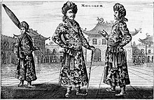 A black-and-white print depicting three standing men wearing turbans, a long robe with a sash, and shoes with rising pointed tips, against an architectural background of buildings with roofs that point upwards. The man on the left, slightly in the background, is carrying a long folded umbrella on his left shoulder. The one in the center, who faces the viewer, is resting on a cane. The man on the right, seen in profile view, faces the center man.