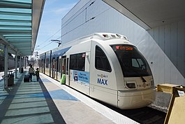 A MAX train stopped with its doors open and passengers boarding it at Portland Airport station