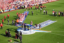 A coloured photograph of a trophy presentation which took place on the Highbury pitch