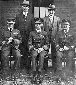Portrait of five men, three in military uniforms and the others in business suits