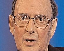 head shot of bespectacled ageing man talking