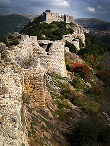 Stone fortress and fortifications built atop a forested, mountain ridge