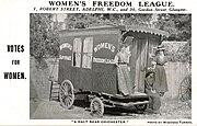 Postcard or posters with an image of women in hats and dresses (two standing and one seated) on the step of a caravan. White writing on the side of the caravan reads "Women's Suffrage" and "Women's Freedom League". The image is captioned "A halt near Chichester." and credited to Winfred Turner.