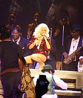 Aguilera wearing a red outfit performing atop a piano