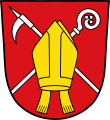 Gemeinde Krün In Rot eine goldene Mitra mit abhängenden Bändern, der schräg gekreuzt ein silberner Flößerhaken und ein silberner Abtsstab unterlegt sind.