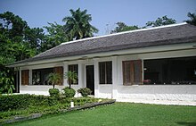 A white-washed bungalow with a lawn in front