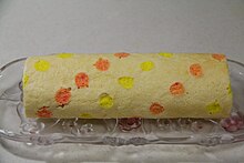 Rolled cake with orange and yellow dots over the surface