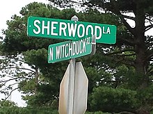 Sign reading 'Sherwood La' in one direction and N Witchduck Rd' in the other, in white lettering on a green background