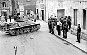 A French-built Hotchkiss H38 tank (captured by the Germans after 1940), passes through the streets of the city center.