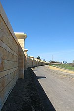 A wall can be seen at the left the image, curving towards the center of the image. A path is located to the right of the wall.