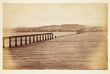 Sepia photograph of the Tay Bridge after the accident. Shot from the South it shows the middle section of the bridge to be missing.
