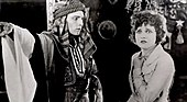 Black and white screenshot from the film The Sheik, with the man in Arab costume and the woman in Western clothing.