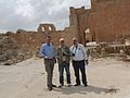 Three men stood in front of stone ruins