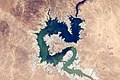 Image 17 Haditha Dam Photograph credit: NASA, Kjell N. Lindgren The Haditha Dam is an earth-filled dam in Iraq, holding back the waters of the Euphrates to create Lake Qadisiyah. The area around Haditha is very arid, with a hot desert climate; the annual precipitation is about 127 millimetres (5 in), mainly occurring during the winter. This photograph, taken from the International Space Station in November 2015, shows the reservoir at a low water level, surrounded by an expanse of dry lakebed; the Haditha Dam is visible near the top of the image. Lake Qadisiyah has a maximum water-storage capacity of 8.3 cubic kilometres (2.0 cu mi) and a maximum surface area of 500 square kilometres (190 sq mi). The associated hydroelectric power station is capable of generating 660 megawatts of electricity, and outlets at the foot of the dam can discharge 3,000 cubic metres (110,000 cu ft) of water per second for irrigation.
