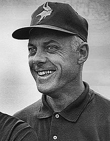 Candid black-and-white head and shoulders photograph of Grant smiling and wearing a Minnesota Vikings baseball cap
