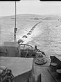 The boom defence net at Scapa Flow being towed into position by two Royal Navy boom defence vessels in 1943.