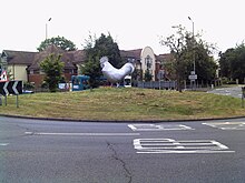 The sculpture surrounded by a large circle of grass and a roundabout