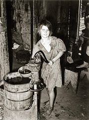 A child drawing water from a hand pump in Oklahoma City, 1939