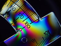 Tension lines of mechanical stress can be visualized in a plastic protractor seen under cross polarized light. Birefringence of the plastic shows colored fringes, a.k.a photoelasticity.