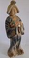 A sancai figurine of a plump lady holding a Dog, Tang dynasty.