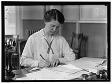 A portrait of Van Kleeck at work at a busy desk with the Russell Sage Foundation before WWI
