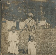 Photograph of man standing outdoors with two girls